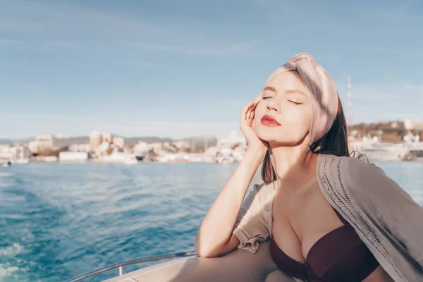 Красива молода жінка насолоджується сонцем і теплом на яхті, закрила очі — стокове фото