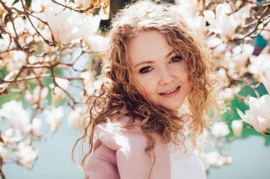 güzel sevimli kıvırcık kadın gülümseyerek ve kamera Park bakarak, poz