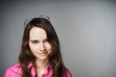 pembe gömlekli kameraya bakarak ve gülümseyen güzel büyüleyici genç kız ofis çalışanı