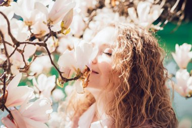 çekici ışınları, bir parkta çiçek açan bir Manolya koklama kıvırcık kadın seviyor bahar ve sıcaklık