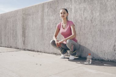 pembe gömlekli hoş ciddi kız koşu sonra dinlenme açık havada, yerde oturur