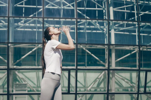 Υψηλό αθλητικό κορίτσι στο sportswear παίρνει δύναμη πριν την προπόνηση, ποτά νερό — Φωτογραφία Αρχείου