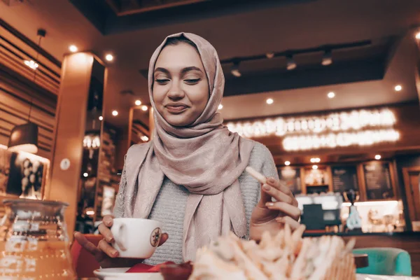 Bájos a fejkendő a fején egy étteremben ízletes ételt muszlim lány mosolyogva — Stock Fotó