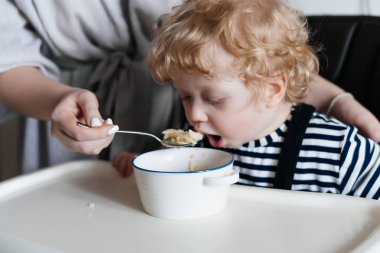 Aile yemeği, Anne mutfakta yararlı yulaf lapası ile küçük kıvırcık oğlu beslemeleri