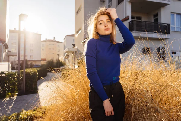 Elegante ragazza modello biondo in maglione blu in posa al sole all'aperto, street style — Foto Stock