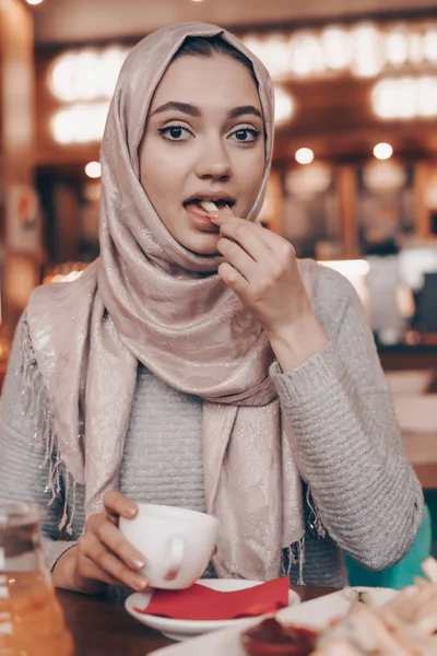 Elegáns Arab lány fején fejkendőt ebédel egy étteremben, beszél a telefonon — Stock Fotó