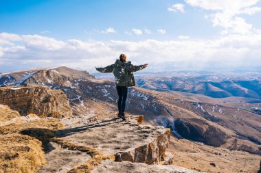 etkin bir genç kız, uçurumun kenarında duruyor dev dağlarla ve temiz hava, seyahat sever
