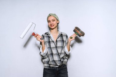 Daire, onarım yapıyor güzel genç kız ressam holding bir fırça ve silindir duvarları boyama için