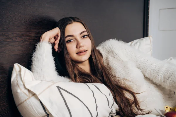 Linda menina doce em pijama branco, com cabelos longos deitado na cama e descansando — Fotografia de Stock