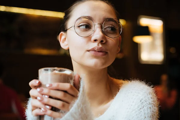 Okouzlující roztomilá dívka v brýle nápoj lahodné horké latte v kavárně — Stock fotografie