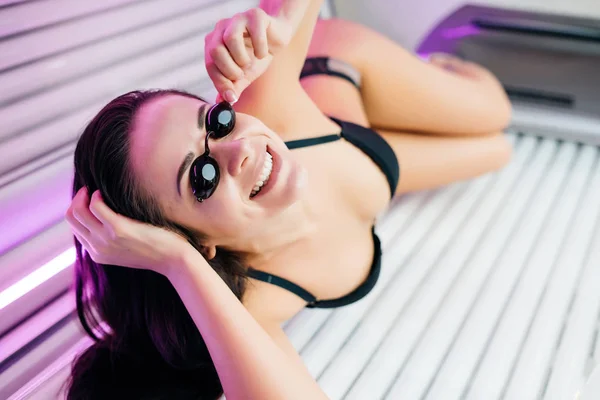 Mooie slanke brunette meisje zonnebaden in een horizontale looien bed, het dragen van bril — Stockfoto