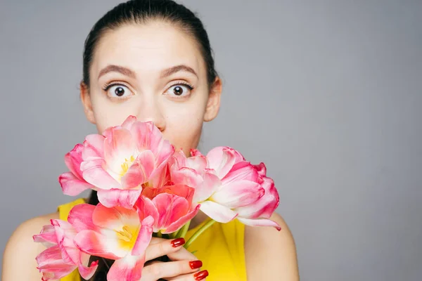 Heerlijk verrast meisje houdt in haar handen geurige roze bloemen en poseren — Stockfoto