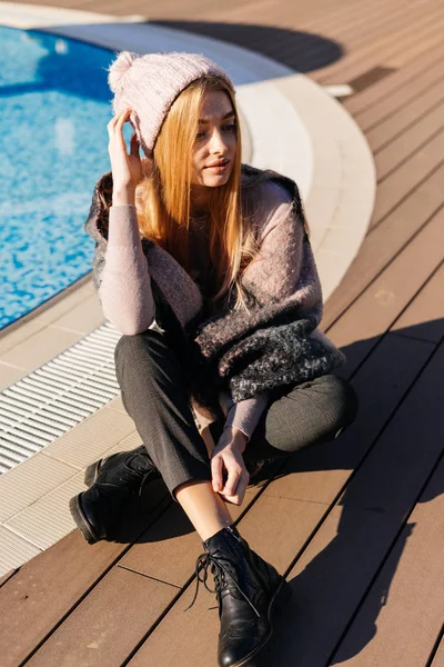Стильная блондинка в шляпе наслаждается весной и теплом у синего бассейна — стоковое фото