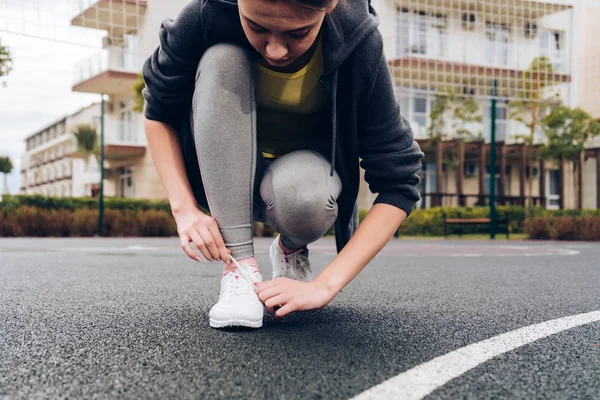 Slim atletische meisje verbindt haar schoenveters op haar sneakers, voorbereiden op een run — Stockfoto