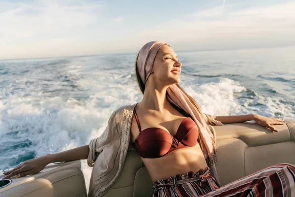 Güneş ve tatil mutlu zengin kadının onun yatta dinlenme bir kırmızı mayo