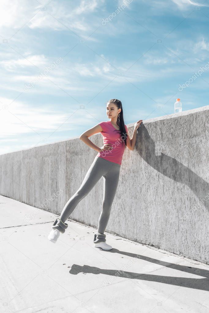 slim athletic girl doing leg exercises outdoors, wants a beautiful shape