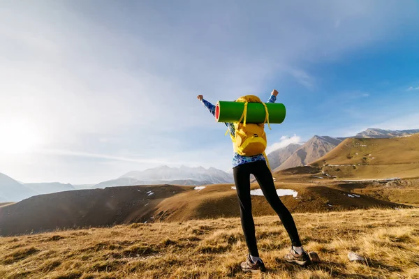 Aktives junges Mädchen reist mit Rucksack und Zelt durch die Kaukasusberge, hebt die Hände nach oben — Stockfoto