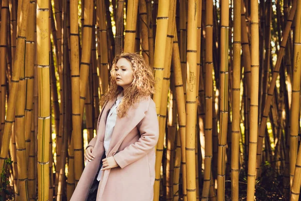 güzel kıvırcık kadın bambu ağaçları arka planı poz parkta yürüyor