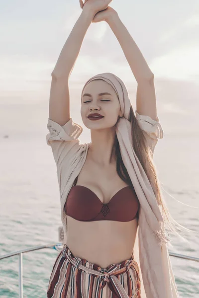 Hermosa joven con lápiz labial rojo disfruta de la calidez y salir en el mar, cierra los ojos y sonríe —  Fotos de Stock