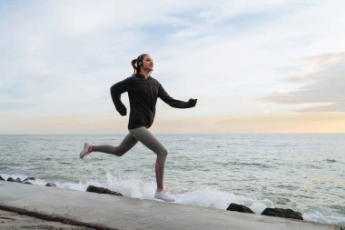 hızlı ince kız deniz kenarında çalışır, kulaklıklar müzik dinler, kilo vermek istiyor