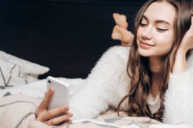 güzel uzun saçlı kız beyaz pijama yatağa erken, kendini fotoğraflarını yalan söylüyor
