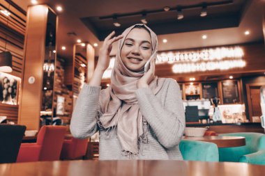 yemeğini restoranda bekliyor başında başörtüsü ile neşeli Arap kız Sevimli, güler