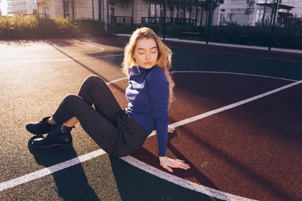 Bela menina confiante com um modelo loira posando em um campo de esportes no sol da manhã — Fotografia de Stock