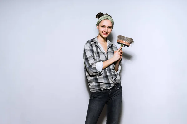 아름 다운 젊은 여자 하 고 수리, 격자 무늬 셔츠에 페인트 브러시와 벽 — 스톡 사진