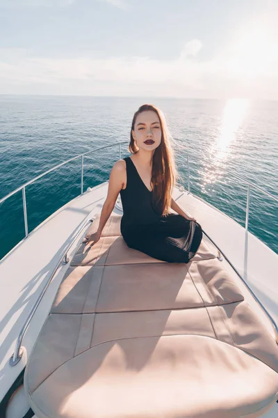 Sexy young woman in black stylish clothes rests on her white yacht, sails on the Caribbean sea — Stock Photo, Image