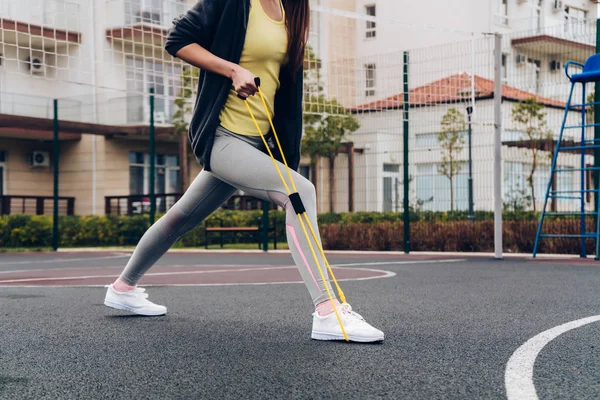 Actief slank meisje doen oefeningen voor de beenspieren op een sportveld — Stockfoto
