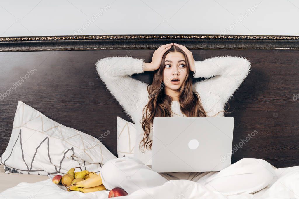 frightened surprised girl watching a scary movie on her laptop