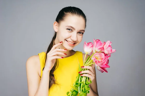 Trendy sarı elbiseli güzel pembe çiçekler, iyi bir ruh hali tutan mutlu gülümseyen kız — Stok fotoğraf