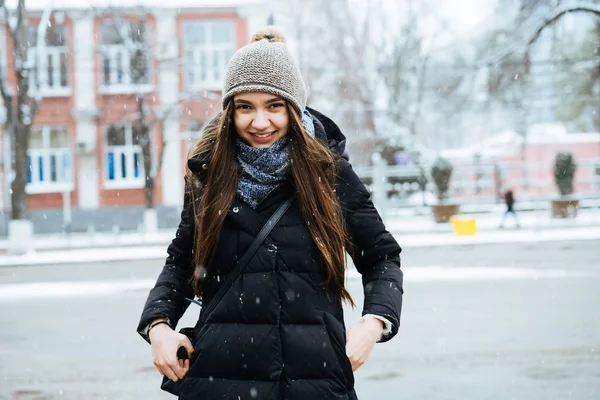Roześmiany młoda dziewczyna z długich włosów spacery po ulicach miasta w zimie, jest zimno — Zdjęcie stockowe