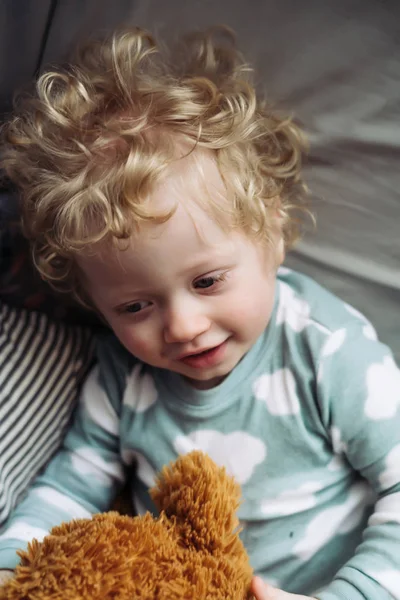 Söt curly-haired barn pojke i blå pyjamas ligger hos mamma och leenden — Stockfoto
