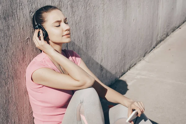 静かな少女、ジョギング後休んでヘッドフォンで音楽を聴く — ストック写真