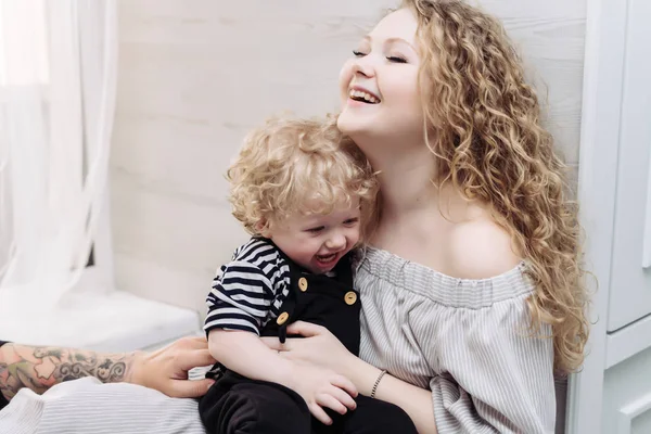 Friendly family, beautiful curly mother playing with her little son, hugging and laughing — Stock Photo, Image