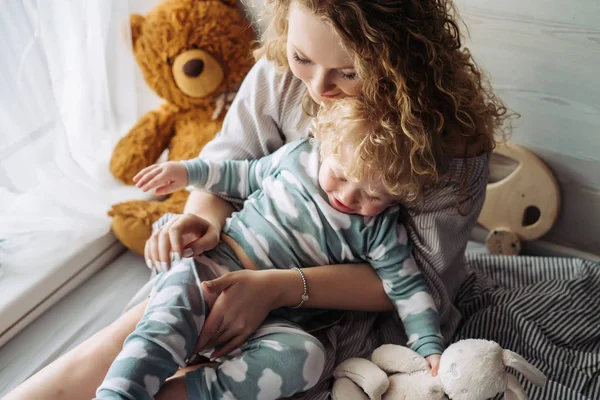 Cuidado joven madre abraza a su pequeño hijo, divertirse — Foto de Stock