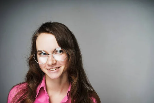 Όμορφη νεαρή γυναίκα υπάλληλος γραφείου σε ένα ροζ πουκάμισο και τα γυαλιά που χαμογελά — Φωτογραφία Αρχείου