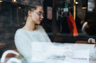 Sevimli Genç kız bardaklarda işten sonra dinlenme rahat bir kafede oturuyor