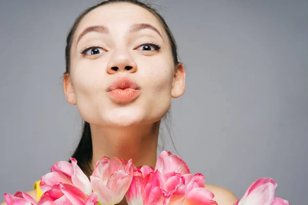 Grappige schattig meisje stuurt een kus, houden een boeket geurende roze bloemen — Stockfoto