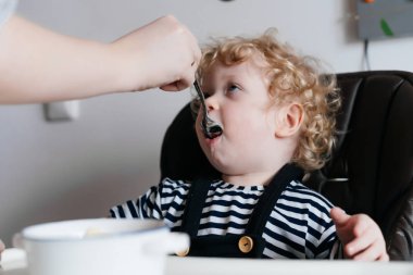 Mutfakta, lezzetli çorba besleme anne oturan küçük kıvırcık bebek çocuk