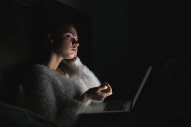 onu laptop sıkıcı bir film izlerken akşamları bir yatakta oturmuş yorgun yorgun genç kız