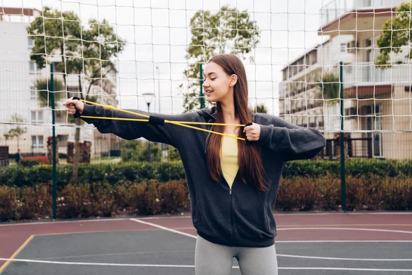 Confiado chica de pelo largo haciendo ejercicios de mano en el campo de deportes — Foto de Stock