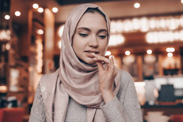 Beautiful Muslim girl eating tasty food in a cafe, wearing a headscarf — Stock Photo, Image