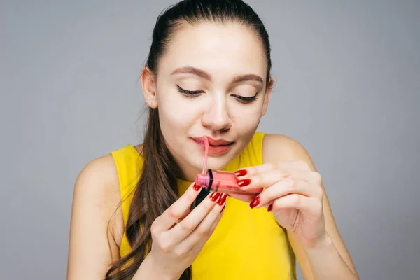 Vacker ung flicka i gul klänning målar läpparna med härligt läppstift — Stockfoto