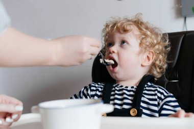 Anne beslemeleri küçük oğlan çocuğunu lezzetli bir çorba ile ailece kahvaltı
