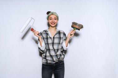 gülümseyen genç kadın bir fırça ve duvar boyama için bir silindir tamir