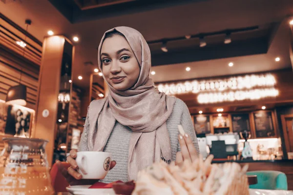 Mignonne fille musulmane dans hijab boit thé parfumé dans le café, souriant — Photo