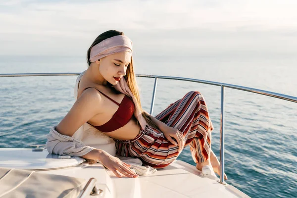 Chica joven con estilo en pantalones de moda está descansando y relajándose en su yate, navegando en el mar —  Fotos de Stock