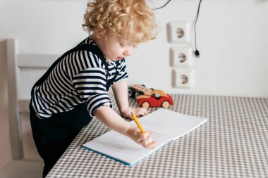etkin kıvırcık küçük oğlu çizer, masada oturur
